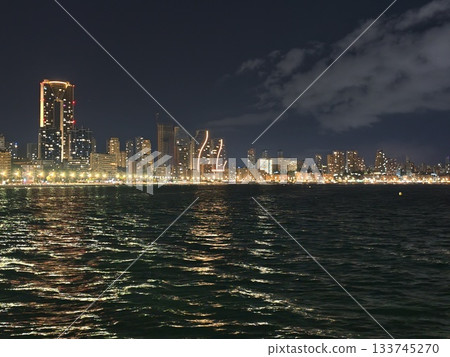 peaceful coastal cityscape illuminated at night with reflective waters and atmospheric clouds 133745270