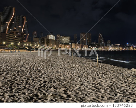 nighttime coastal landscape showcasing city lights and textured sand for travel and patrol themes 133745283