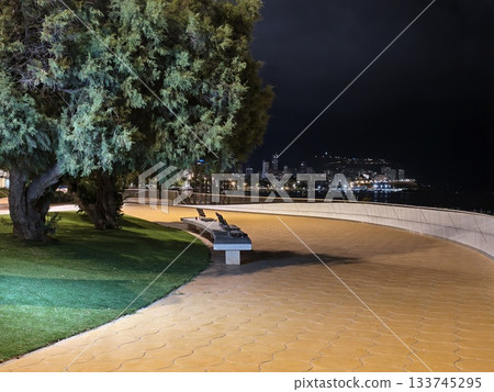 silent promenade at night featuring lone bench overlooking illuminated beach and city skyline silent promenade at night featuring lone bench overlooking illuminated beach and city skyline 133745295