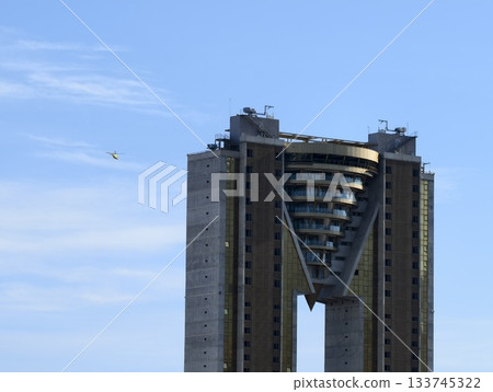 pilot navigates between twin city skyscrapers, vshaped skyscraper with approaching airplane 133745322