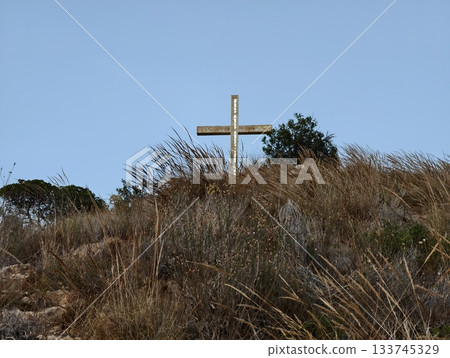 quiet hill adorned with cross and dry grasses, tranquil hillside featuring wooden cross and sparse quiet hill adorned with cross and dry grasses, tranquil hillside featuring wooden cross and sparse 133745329