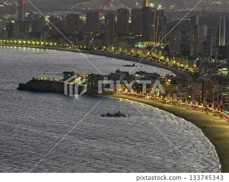 nighttime coastal walk with glowing reflections, shimmering shoreline at twilight with cityscape nighttime coastal walk with glowing reflections, shimmering shoreline at twilight with cityscape 133745343