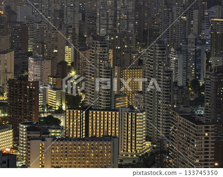 night city with illuminated buildings, urban skyline illuminated with glowing windows and vibrant 133745350