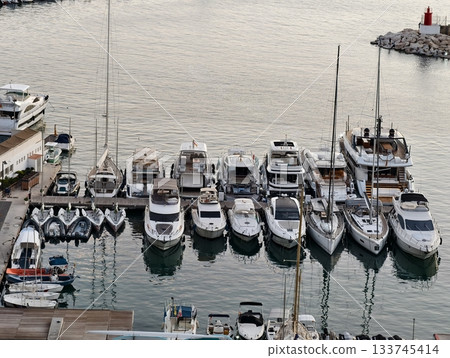 luxurious yachts docked tightly together, premium yachts moored closely at busy harbor scene 133745414