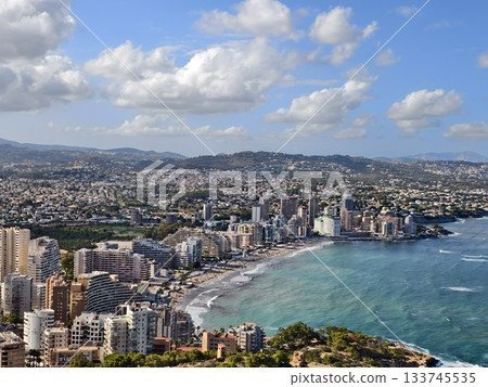 bright coastal scene, sunlit cityscape by shore, golden sunlight illuminates coastal urban landscape 133745535