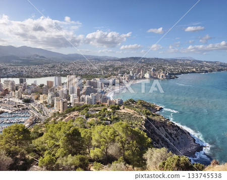coastal aerial view, mountain backdrop behind serene coastal city with resorts and clear skies 133745538