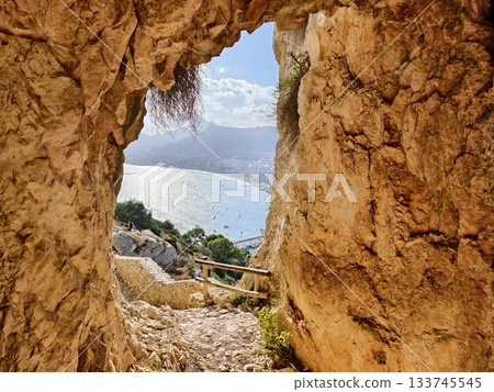 emerald sea beyond tiny cave, narrow rocky entrance reveals glittering emerald waters and distant 133745545