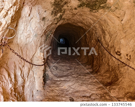 rugged tunnel suggests hidden journeys, narrow rocky corridor hints at adventures in darkness 133745546