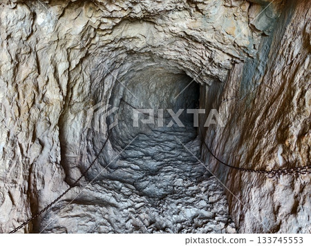 dark rocky underground passageway, enigmatic rugged mineral tunnel extending into dark depths 133745553