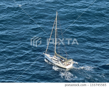 an individual sailor sailing smoothly on serene ocean with focused navigation and quiet waves an individual sailor sailing smoothly on serene ocean with focused navigation and quiet waves 133745565