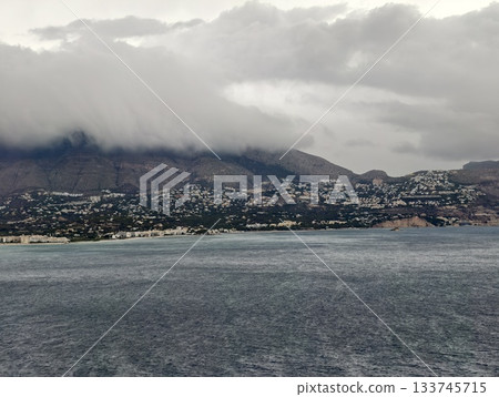 jagged coast with distant harbor, mountainous ridges lead to distant harbor under slatecolored sky 133745715