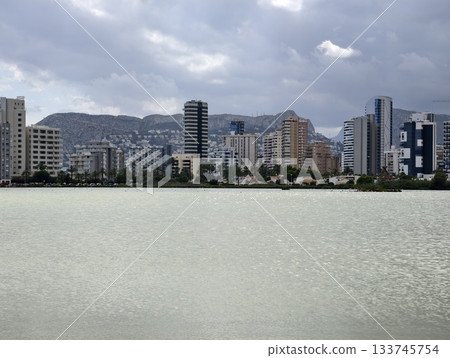 imposing corporate tower with glass facades blending into cloudy sky above financial district 133745754
