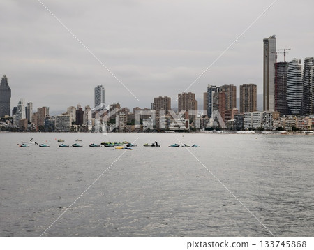 rowing team on waterfront exercises, athletes practice rowing along city waterfront with skyline 133745868