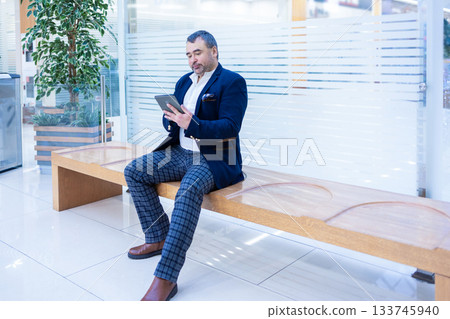 Emotional businessman reading ebook on tablet in bright modern office. High quality photo Emotional businessman reading ebook on tablet in bright modern office. High quality photo 133745940