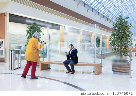 Female photographer shooting a businessman reading an ebook in a bright modern office. High quality photo 133746071