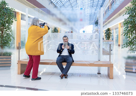 Female photographer shooting a businessman reading an ebook in a bright modern office. High quality photo 133746073