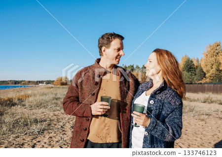 Happy beautiful couple in love enjoying autumn picnic on coast in open air. Weekend and lifestyle concept. High quality photo Happy beautiful couple in love enjoying autumn picnic on coast in open air. Weekend and lifestyle concept. High quality photo 133746123