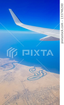 View from the window of plane on blue sky and earth with landscape of desert, sea and canals in Emirates. High quality photo 133746280
