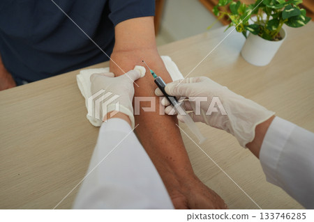 Close up of doctor or nurse taking blood sample from arm vein with vacutainer. syringe to venipuncture the patient Close up of doctor or nurse taking blood sample from arm vein with vacutainer. syringe to venipuncture the patient 133746285