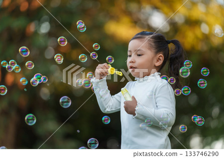 happy toddler girl blowing soap bubbles in park happy toddler girl blowing soap bubbles in park 133746290