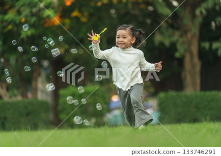 happy toddler girl running and playing soap bubble in park happy toddler girl running and playing soap bubble in park 133746291