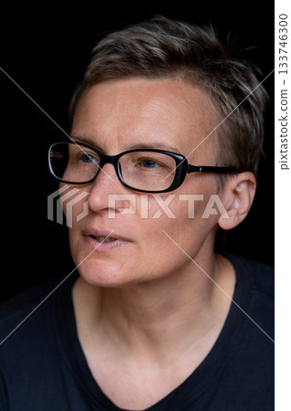 Portrait of caucasian woman with short haircut and black-rimmed glasses on black background, close-up. Emotions on face. High quality photo 133746300