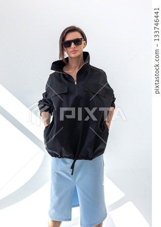 Elegant woman in black windbreaker jacket and light blue skirt on white background. Fashionable female style. Studio photography. Vertical photo. High quality photo Elegant woman in black windbreaker jacket and light blue skirt on white background. Fashionable female style. Studio photography. Vertical photo. High quality photo 133746441