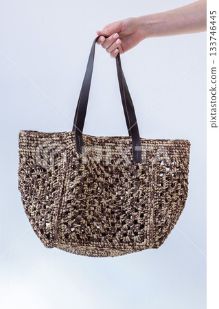 Female hand holding fashionable woven bag. Fashion and luxury accessories. Vertical photo. High quality photo Female hand holding fashionable woven bag. Fashion and luxury accessories. Vertical photo. High quality photo 133746445