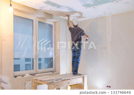 Worker make repairs in new apartment. Man plaster walls and ceilings. High quality photo 133746649