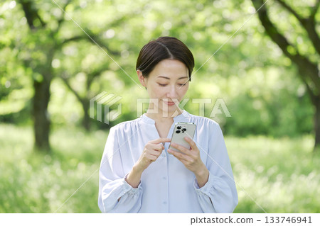 A woman in her 40s using a smartphone outdoors 133746941