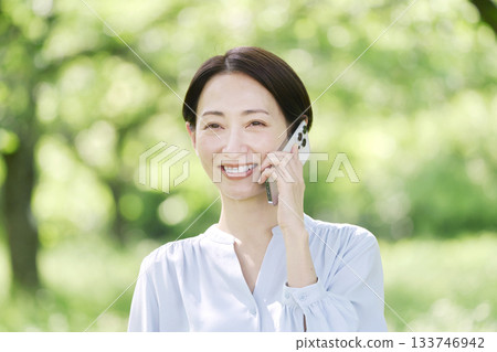 Woman making a phone call on a smartphone outdoors 133746942