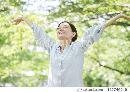 A woman in her 40s taking a deep breath outdoors A woman in her 40s taking a deep breath outdoors 133746946