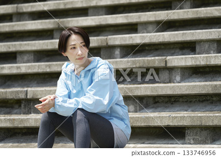 Sportswoman sitting on outdoor stairs Sportswoman sitting on outdoor stairs 133746956