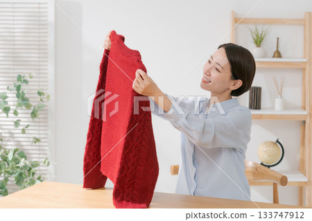一位女士正在攤開她的紅色毛衣 133747912