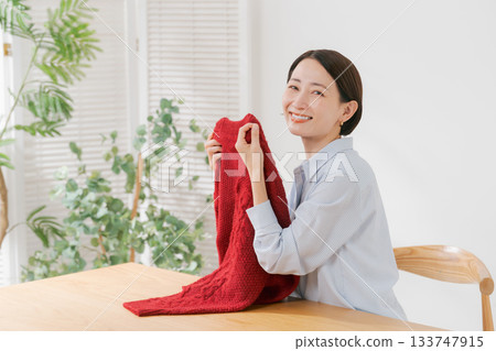 一位女士正在攤開她的紅色毛衣 133747915