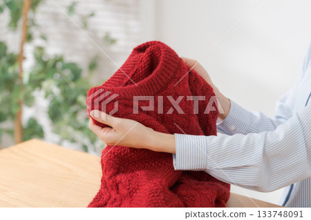 A woman's hands folding a sweater 133748091