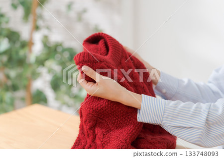 A woman's hands folding a sweater 133748093
