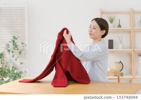 A woman's hands folding a sweater 133748094