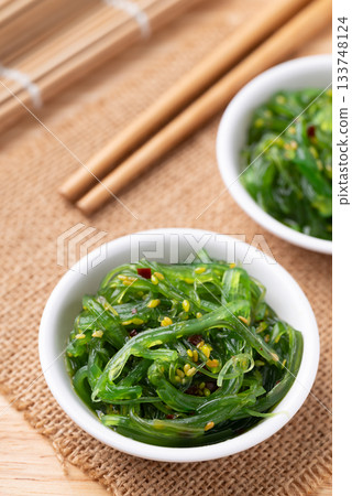 Wakame seaweed salad with sesame seed in a bowl with chopsticks 133748124