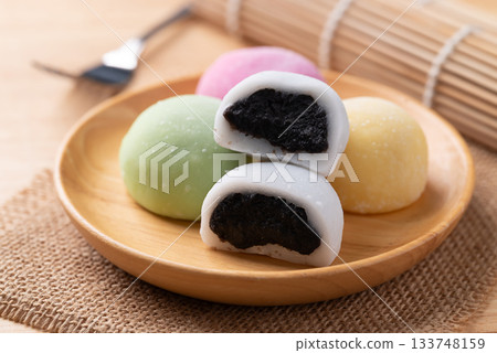 Daifuku mochi (Traditional Japanese sweet) stuffed with black sesame seed on wooden plate 133748159