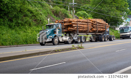 Astoria, Oregon, USA - May 21, 2019: Kenworth Tridem. Deforestation and environmental impact. Logging and forest harvesting. Harvesting of timber or deforestation. Kenworth Tridem with timber Astoria, Oregon, USA - May 21, 2019: Kenworth Tridem. Deforestation and environmental impact. Logging and forest harvesting. Harvesting of timber or deforestation. Kenworth Tridem with timber 133748249