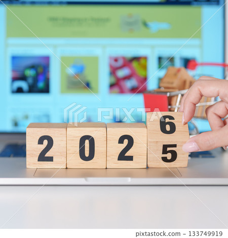 2025 end year to Happy New Year 2026 block with shopping trolley cart on table. E commerce, online shopping, finance, consumer economy and celebration concepts 133749919