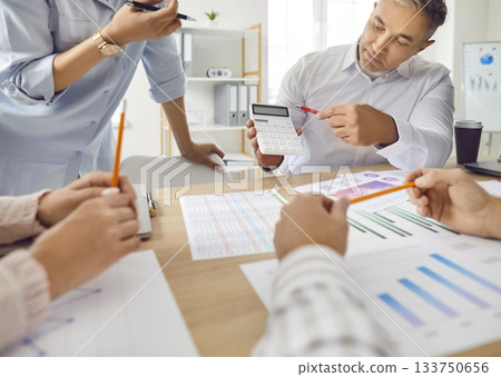 Businessman using a calculator to present financial results to his team. 133750656