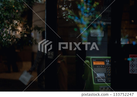 Public telephone and illumination reflected on the glass door Public telephone and illumination reflected on the glass door 133752247