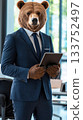 A confident brown bear stands in a well-lit modern office, dressed in a tailored navy-blue three-piece suit while holding a high-end tablet 133752497