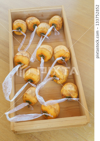 Making dried persimmons: Leave the branch in a T-shape and attach string to the peeled persimmon. 133752852