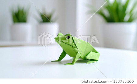 A minimalist composition of a green origami frog placed on a white table 133753100