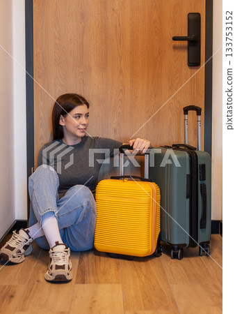 Woman traveling sitting on floor waiting with luggage 133753152