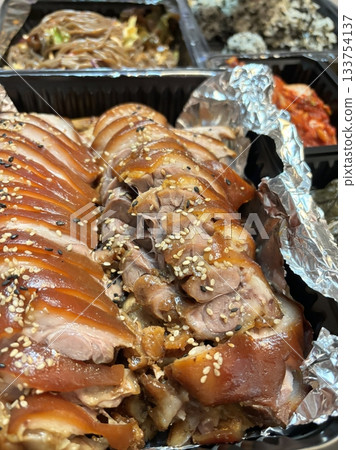 Jokbal, a Korean dish of braised pork hock, slow-cooked in a rich, savory sauce with soy, garlic, and spices. Tender and flavorful, it’s often served with lettuce wraps, garlic, and ssamjang 133754137