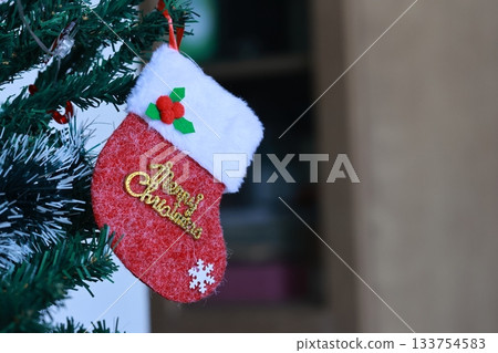 A red Christmas stocking with the words Merry Christmas hanging on the Christmas tree. A red Christmas stocking with the words Merry Christmas hanging on the Christmas tree. 133754583